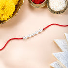 Close-up of Pearl Charm Rakhi in Sterling Silver featuring red - white thread, pearl work, and rhodium plating – ideal for Raksha Bandhan | Peora
