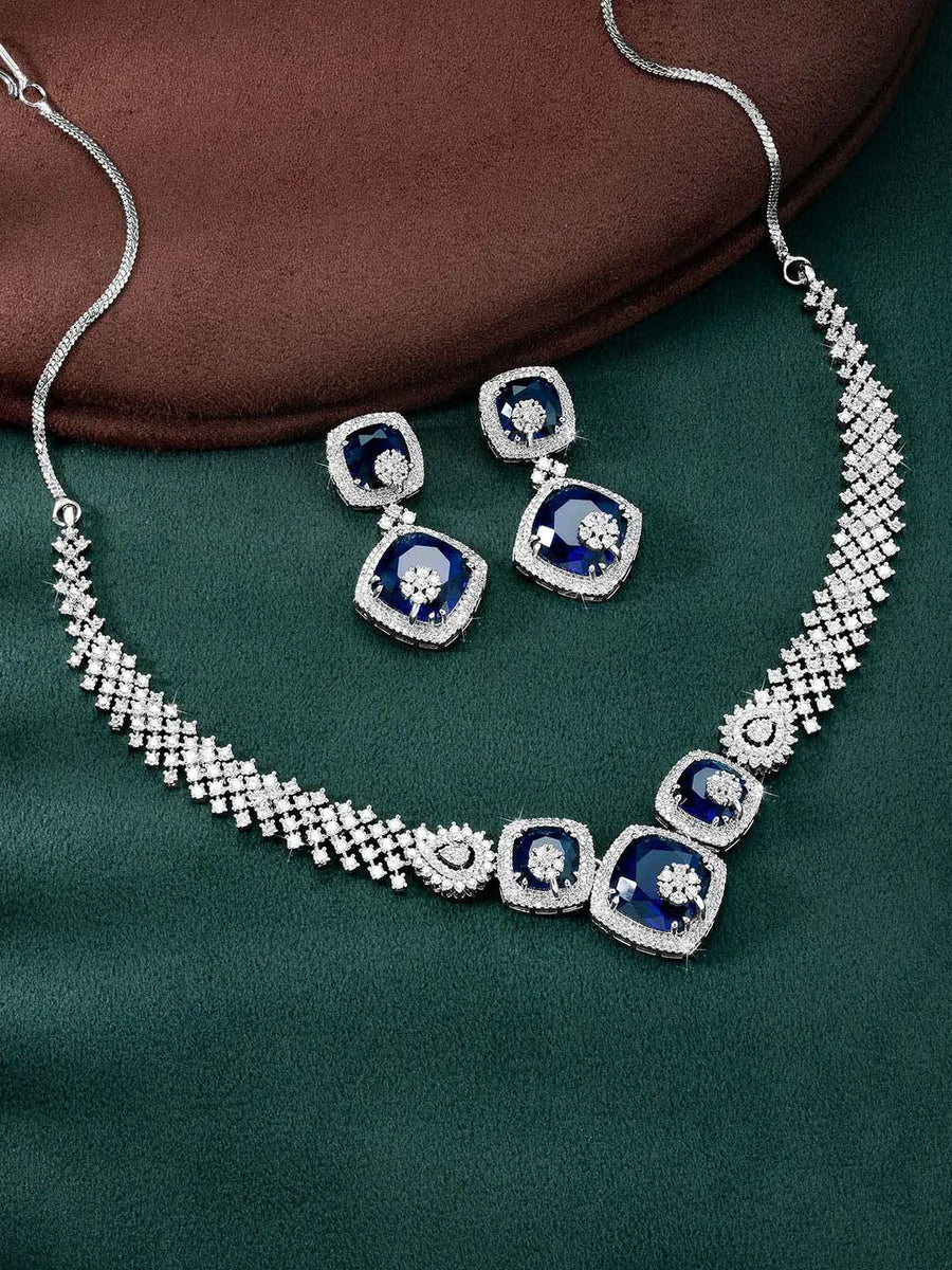 Exquisite CZ Necklace Sets Collection. A silver-colored necklace and earring set with blue and white cubic zirconia stones.
