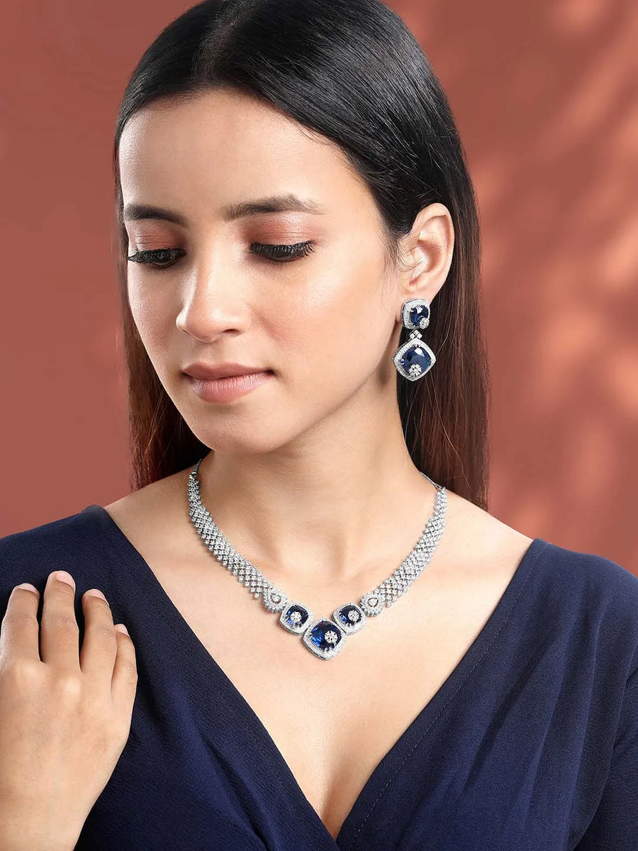 Exquisite CZ Necklace Sets Collection. A silver-colored necklace and earring set with blue and white cubic zirconia stones.