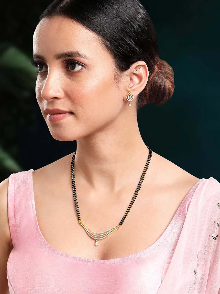 CZ Studded Traditional Mangalsutra Set. A traditional mangalsutra set with black beads and gold-color plating, zirconia stones, & matching earrings.