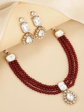 Graceful Layers with Kundan Set. Gold-plated red beaded necklace set with large white stones and matching drop earrings.