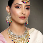 Bridal Bliss Kundan Pearl Necklace Set. Gold-plated Kundan bridal necklace set with colorful beads, matching jhumka earrings, and maang tikka. Perfect for weddings and festive occasions.