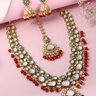 Nature's Glisten Green Necklace Set by Peora. Gold-plated red & Green Kundan necklace set with matching earrings and maang tikka, featuring red beads & white pearls.