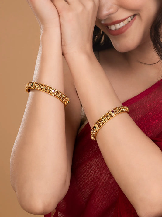 Woman wearing gold bracelets with rani pink accent on a beige background rom Peora