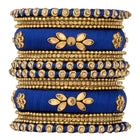 A set of blue and gold colored alloy bangles with kundan embellishments displayed on a cylindrical object.