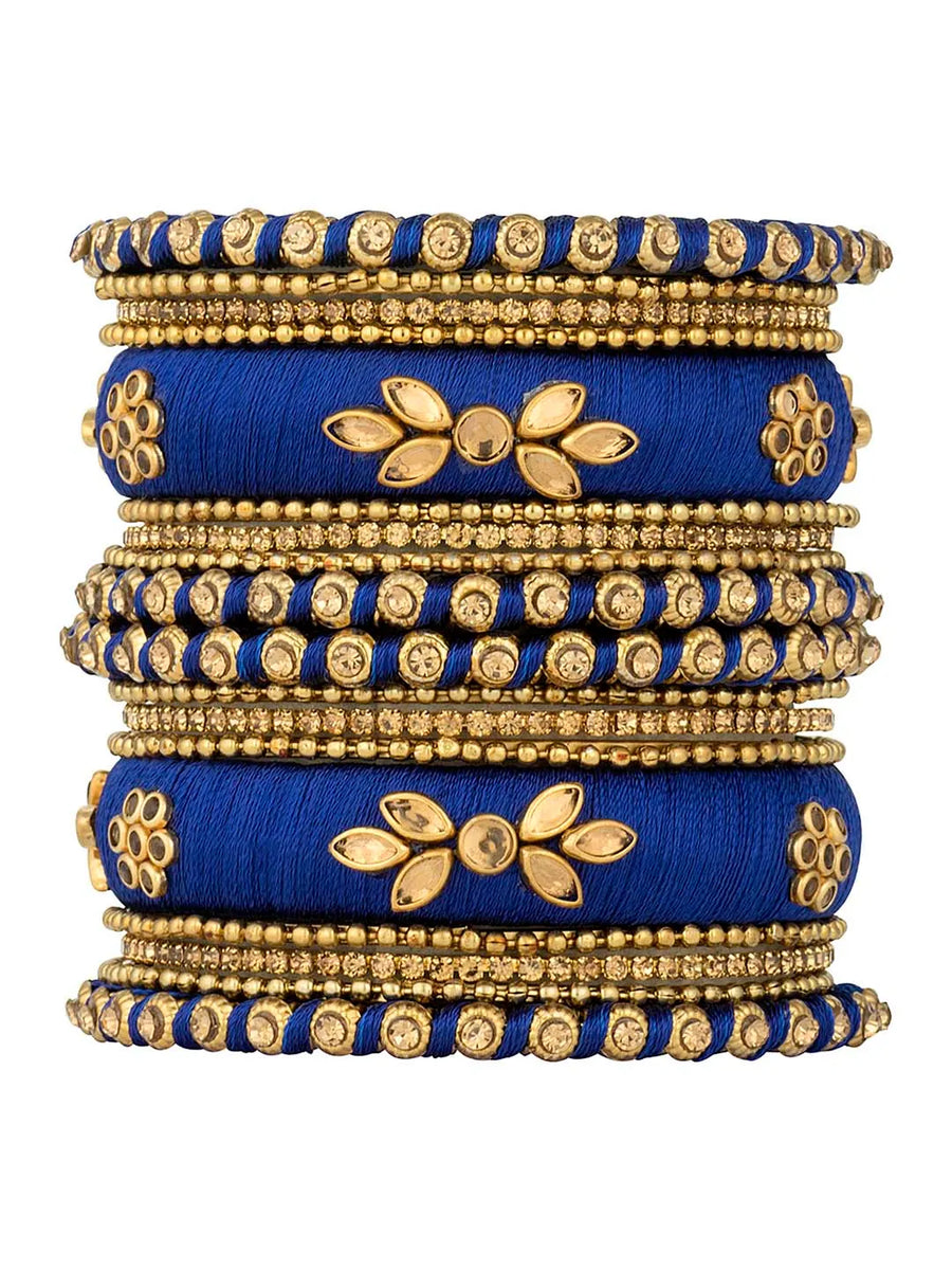 A set of blue and gold colored alloy bangles with kundan embellishments displayed on a cylindrical object.
