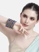 A set of blue and gold colored alloy bangles with kundan embellishments displayed on a cylindrical object.