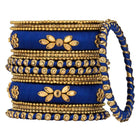 A set of blue and gold colored alloy bangles with kundan embellishments displayed on a cylindrical object.