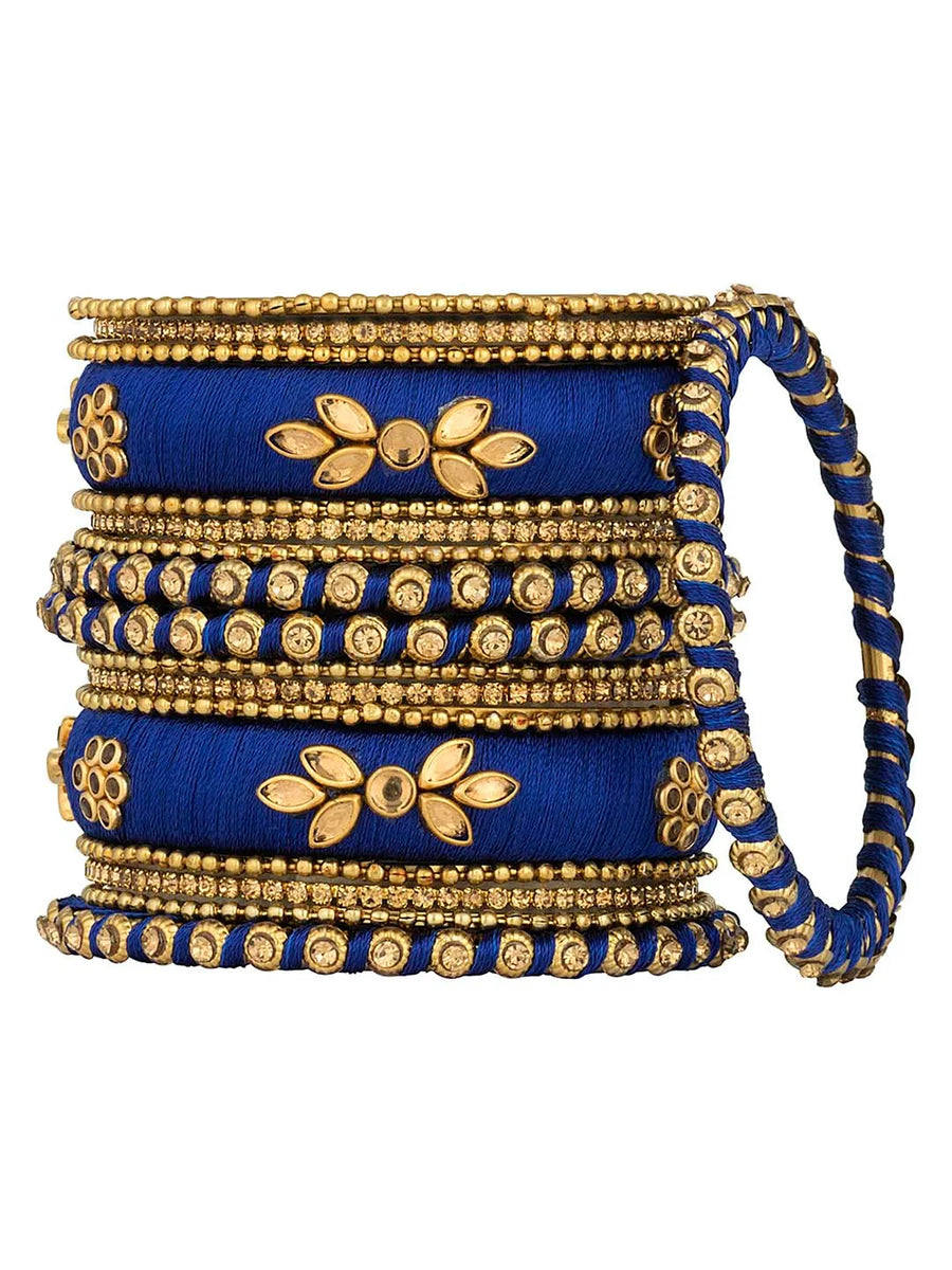 A set of blue and gold colored alloy bangles with kundan embellishments displayed on a cylindrical object.
