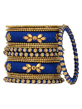 A set of blue and gold colored alloy bangles with kundan embellishments displayed on a cylindrical object.
