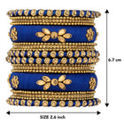 A set of blue and gold colored alloy bangles with kundan embellishments displayed on a cylindrical object.
