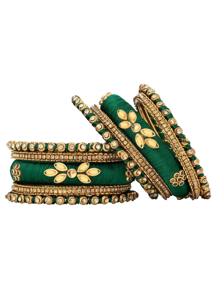 A set of Green and gold colored alloy bangles with kundan embellishments displayed on a cylindrical object.