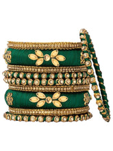 A set of Green and gold colored alloy bangles with kundan embellishments displayed on a cylindrical object.