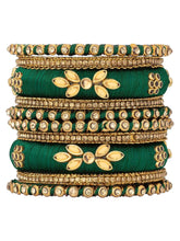 A set of Green and gold colored alloy bangles with kundan embellishments displayed on a cylindrical object.