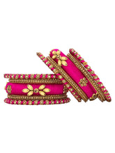 A set of Pink and gold colored alloy bangles with kundan embellishments displayed on a cylindrical object.