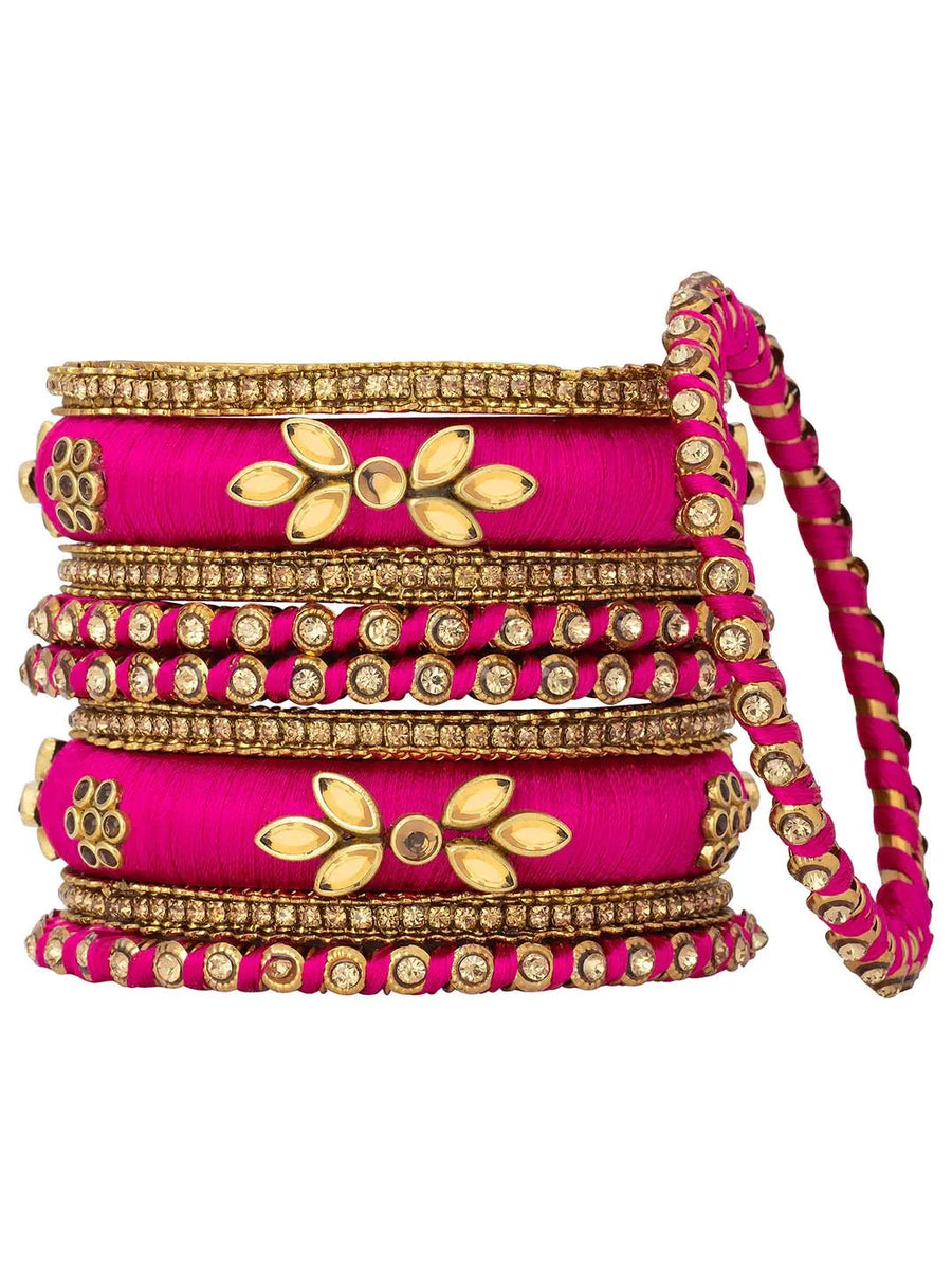 A set of Pink and gold colored alloy bangles with kundan embellishments displayed on a cylindrical object.