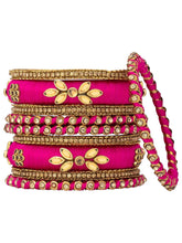 A set of Pink and gold colored alloy bangles with kundan embellishments displayed on a cylindrical object.