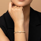 Woman wearing a gold floral kada bracelet on a beige background by Peora