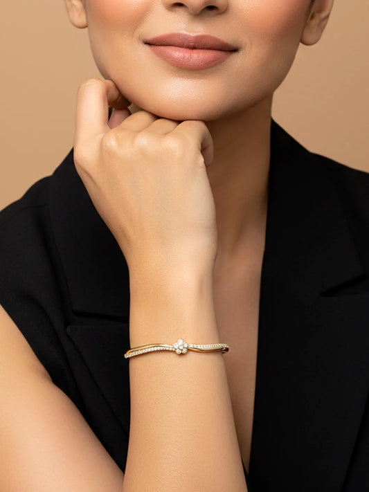 Woman wearing a gold floral kada bracelet on a beige background by Peora