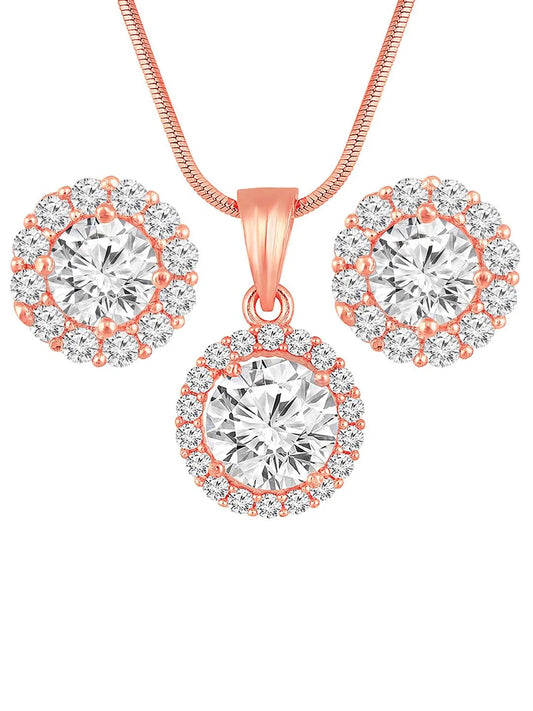 A rose gold-colored pendant necklace with a round cubic zirconia solitaire pendant accompanied by a pair of matching earrings, displayed on a pink cushion.
