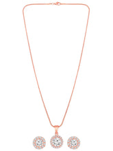 A rose gold-colored pendant necklace with a round cubic zirconia solitaire pendant accompanied by a pair of matching earrings, displayed on a pink cushion.