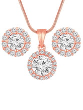A rose gold-colored pendant necklace with a round cubic zirconia solitaire pendant accompanied by a pair of matching earrings, displayed on a pink cushion.