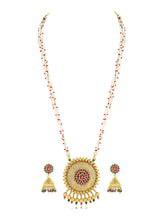 A traditional Indian necklace set with gold-colored metalwork and synthetic stones, accompanied by matching earrings, displayed on a white fabric surface.