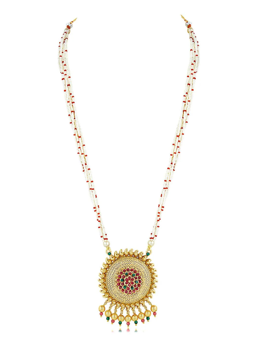 A traditional Indian necklace set with gold-colored metalwork and synthetic stones, accompanied by matching earrings, displayed on a white fabric surface.