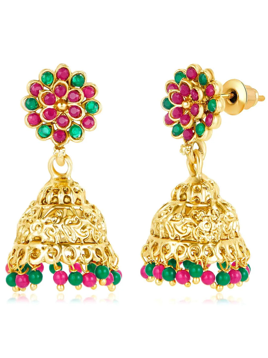 A traditional Indian necklace set with gold-colored metalwork and synthetic stones, accompanied by matching earrings, displayed on a white fabric surface.